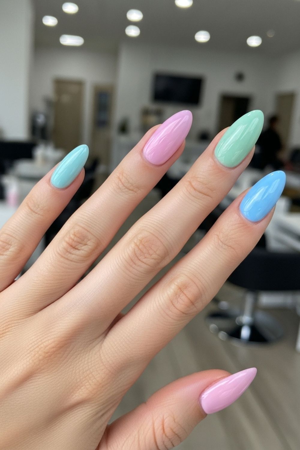 “Close-up of a straight hand with almond-shaped gel nails in glossy pastel shades, smooth glass-like finish, modern nail salon background softly blurred.”