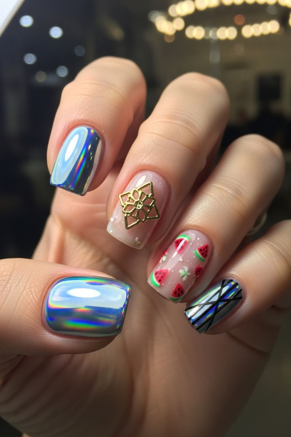“Close-up of hands with trendy nail designs, including holographic chrome, fruity summer art, and bold accent nails. Nails are sharply focused with a softly blurred modern salon background.”